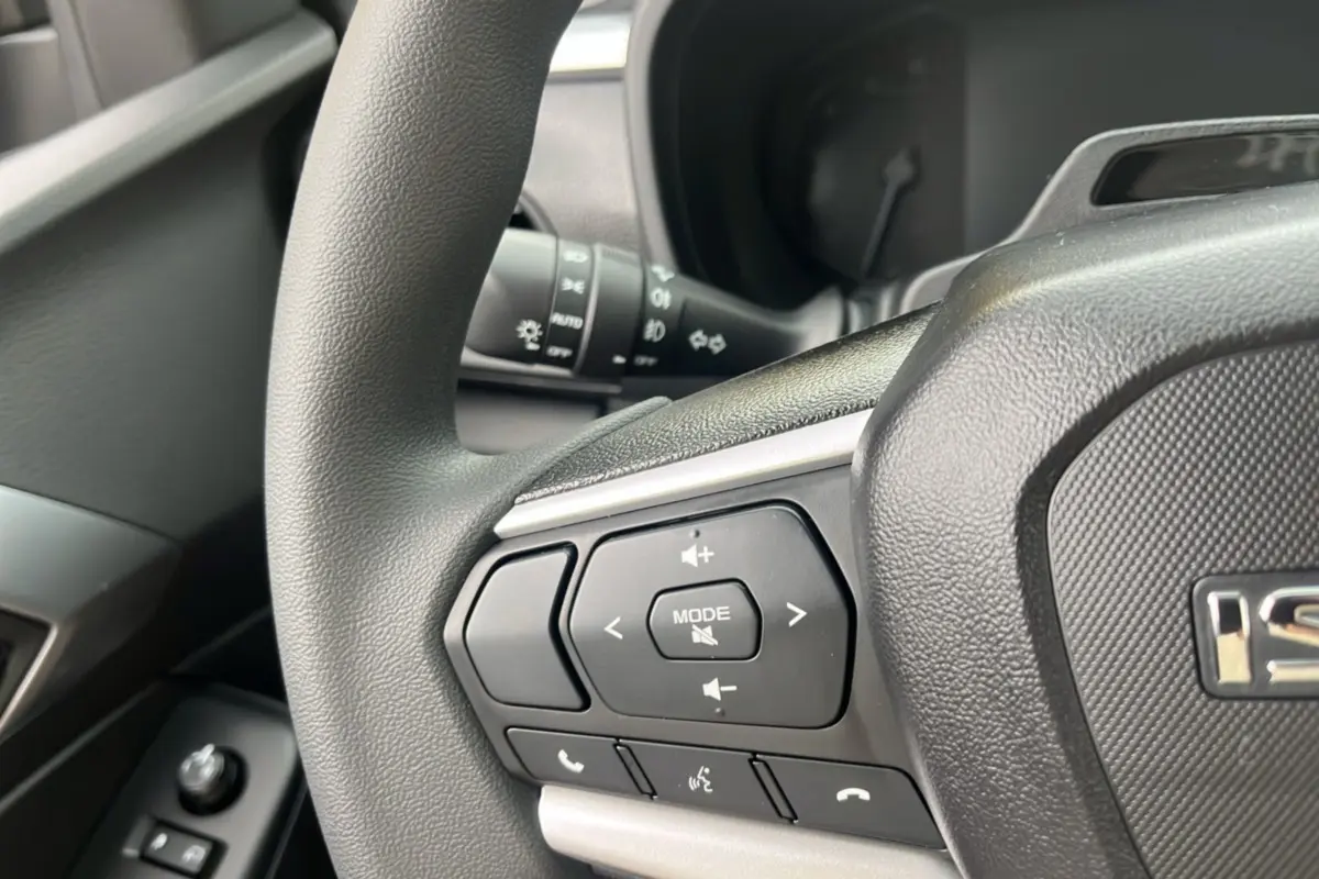 Gros plan sur le volant multifonctions noir de l'Isuzu D-MAX 2026, avec commandes audio et téléphone intégrées.