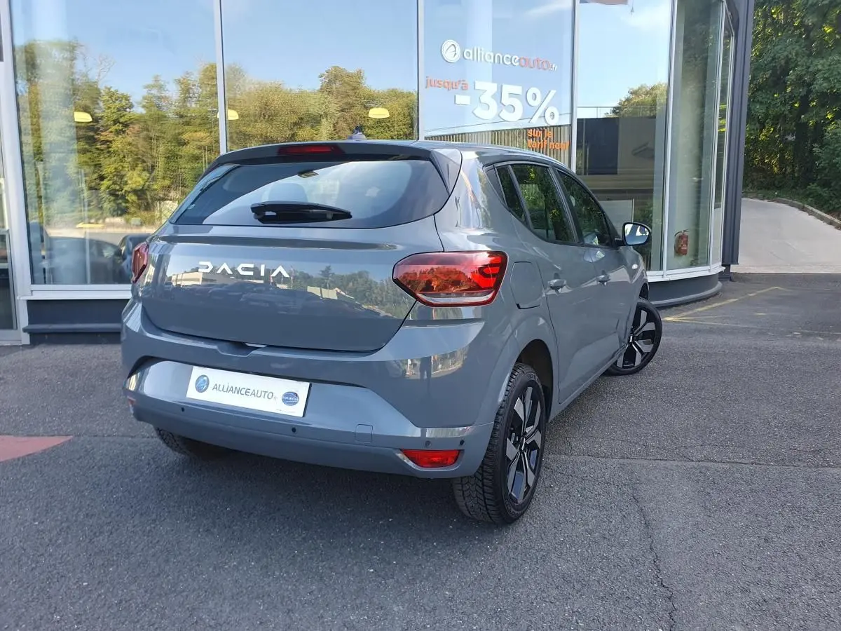 Vue 3/4 arrière droite d'une Dacia Sandero 2024 gris urbain avec jantes alu 16 pouces et feux arrière LED.