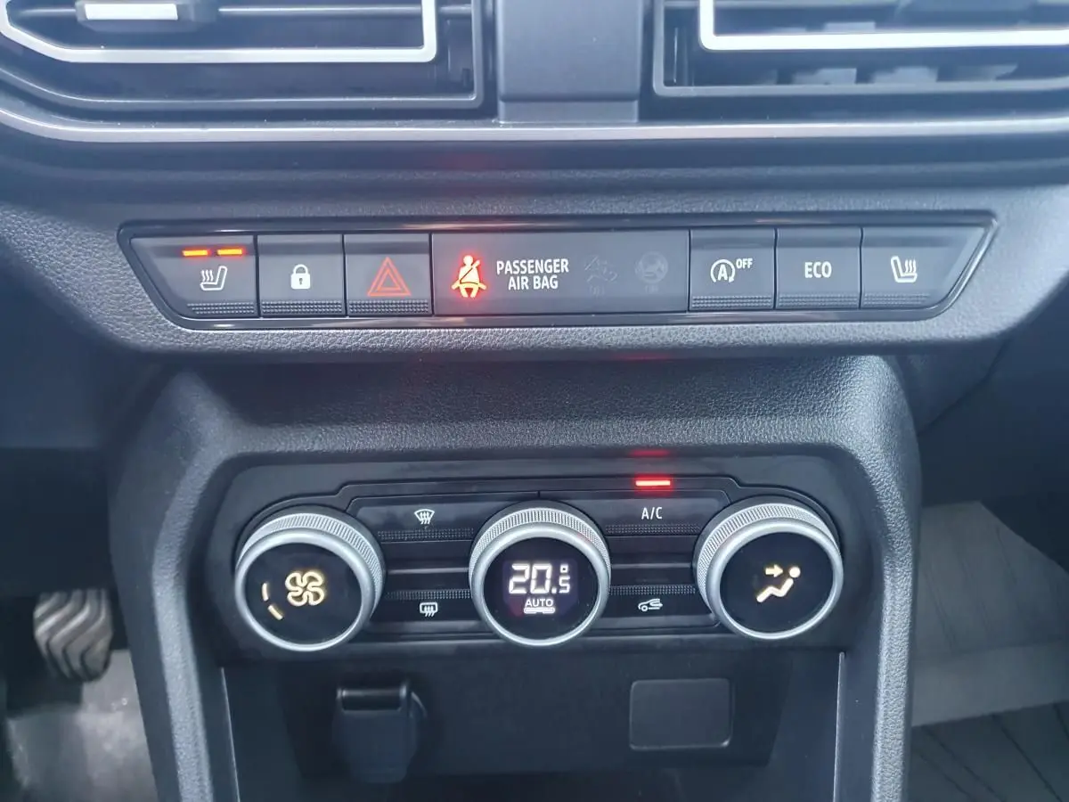 Tableau de bord de Dacia Sandero 2024, vue rapprochée des commandes de climatisation automatique et des boutons de sécurité.