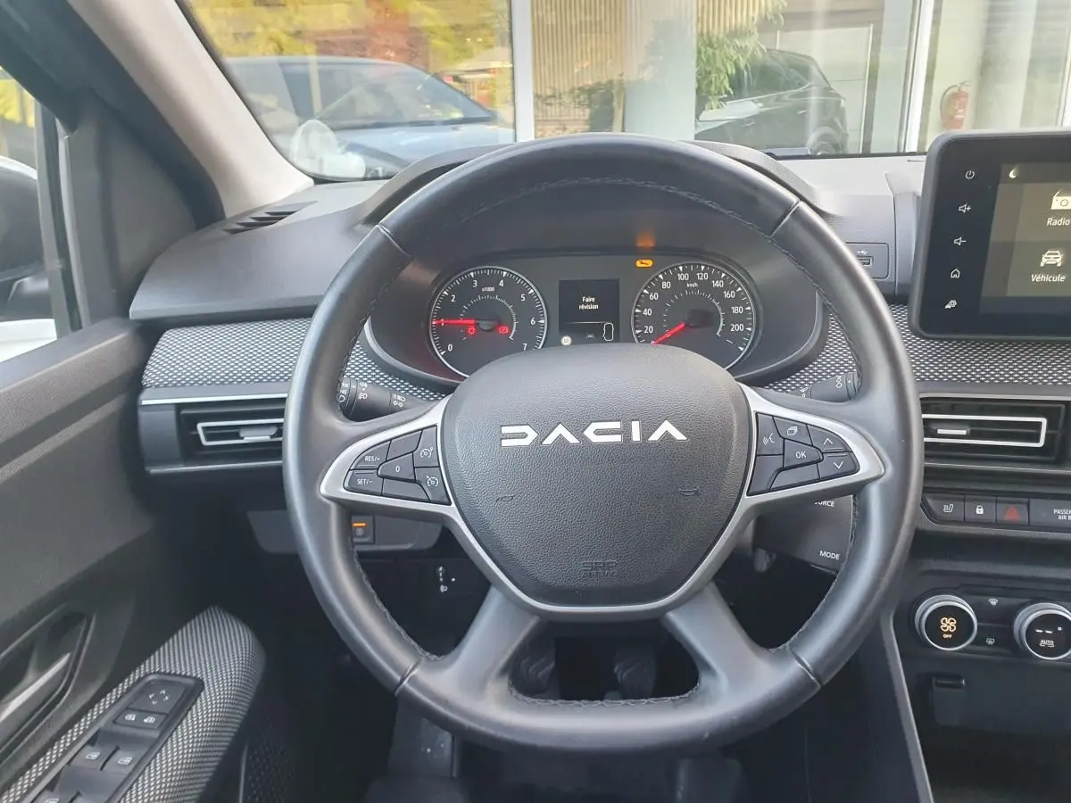 Vue rapprochée du volant multifonction noir de la Dacia Sandero 2024 avec tableau de bord et écran tactile.