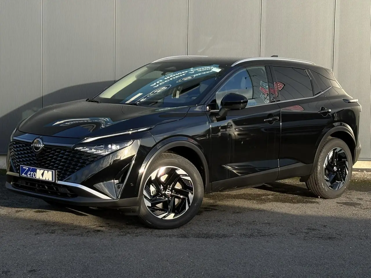 Nissan Qashqai noir Kuro en 3/4 avant droit, avec jantes alliage noires et calandre distinctive brillante.