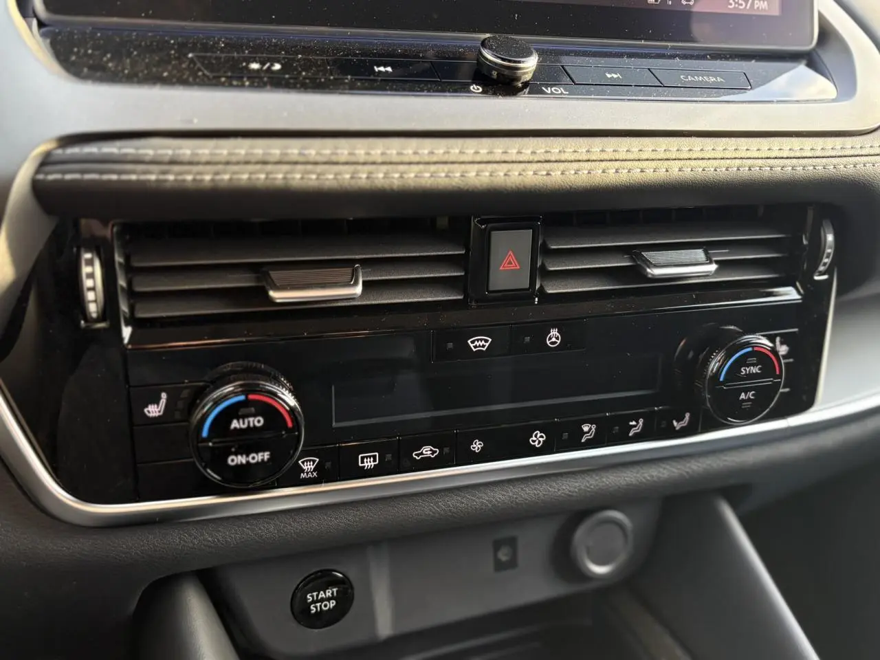 Vue rapprochée de la console centrale du Nissan Qashqai noir, montrant les commandes de climatisation automatique bi-zone et bouton Start/Stop.
