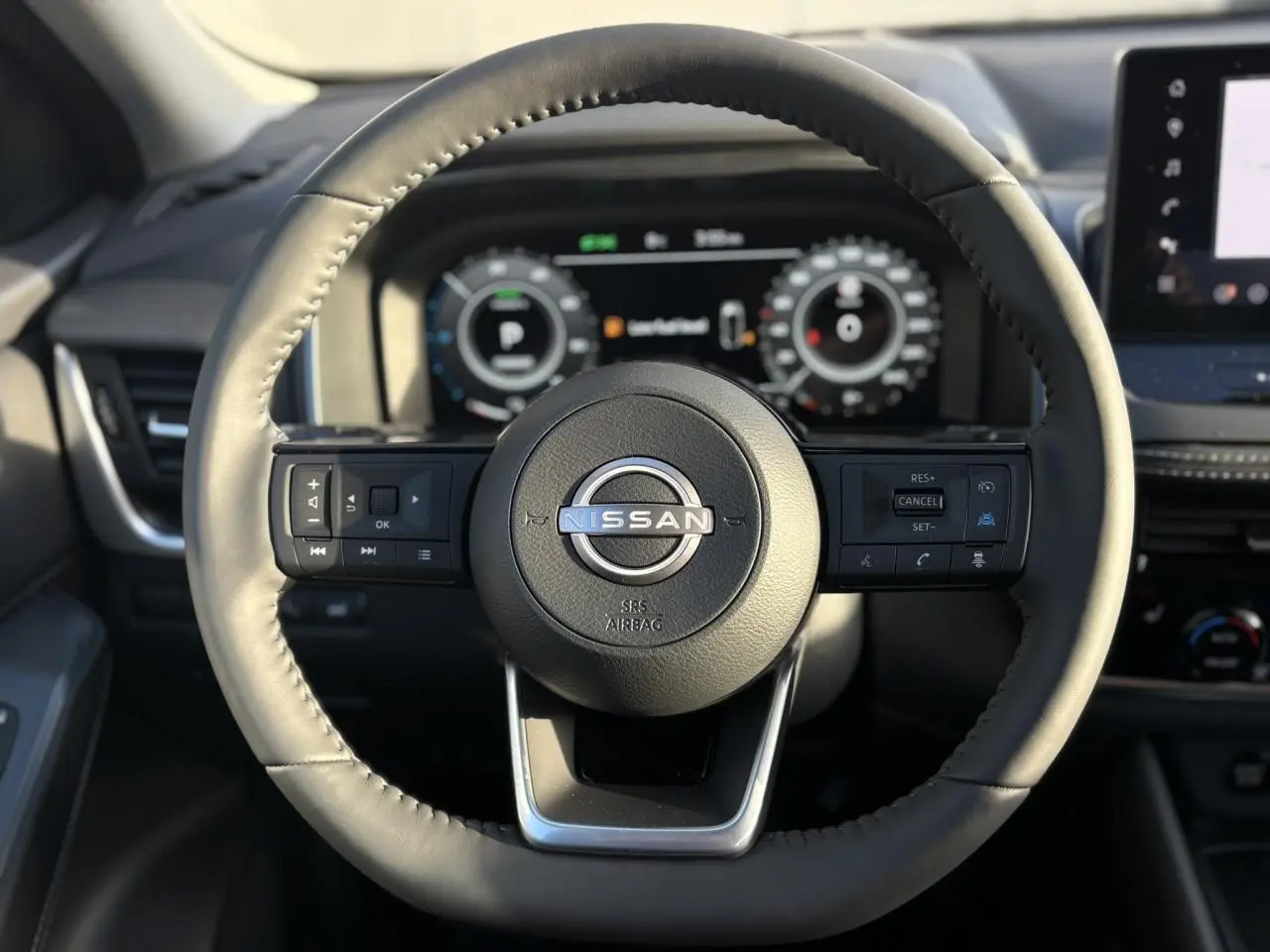 Vue rapprochée du volant noir en cuir du Nissan Qashqai 2026 avec commandes intégrées et tableau de bord numérique.