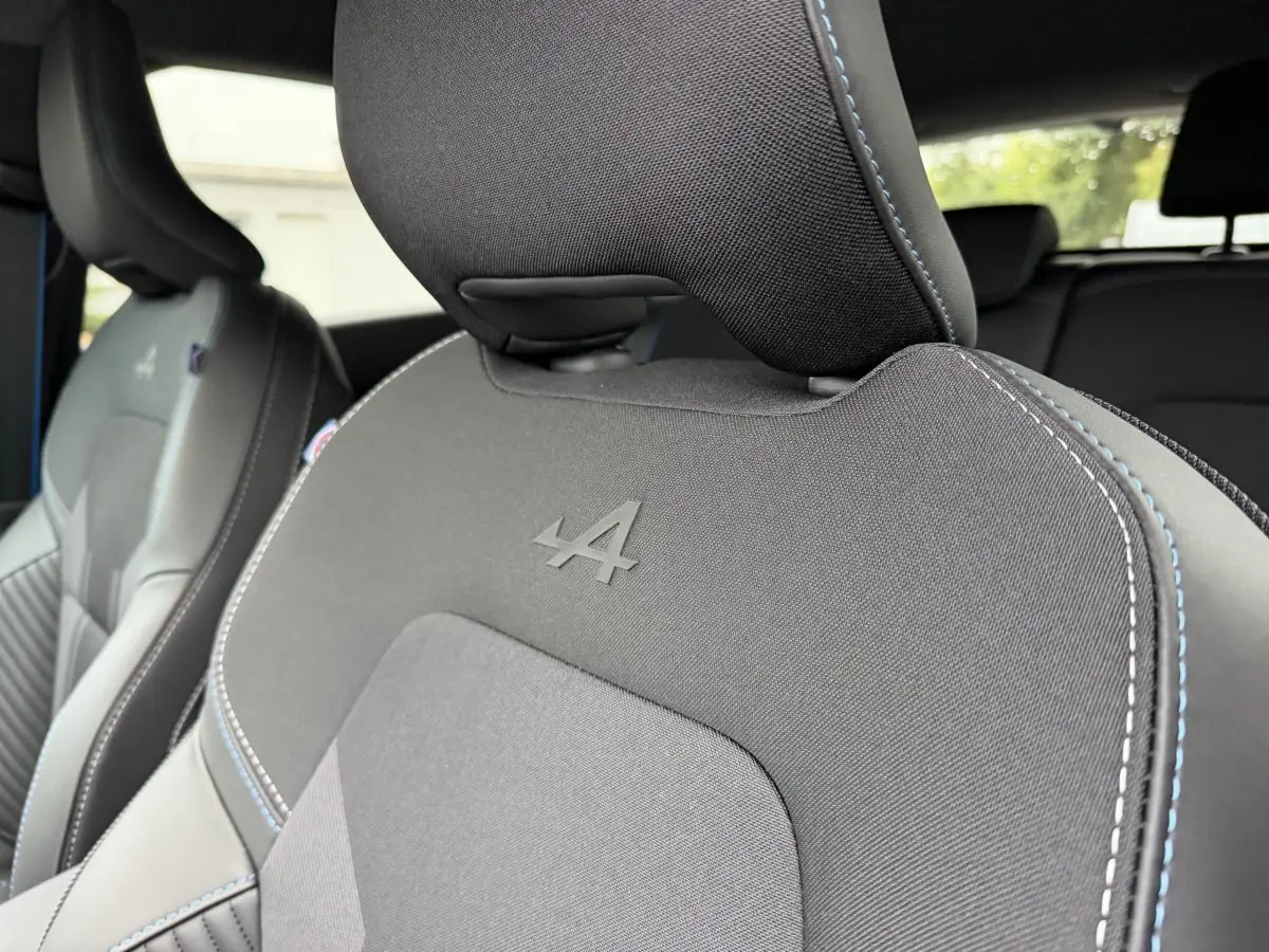 Gros plan sur les sièges avant noirs du Renault Captur Esprit Alpine, avec logo Alpine embossé et surpiqûres bleues.