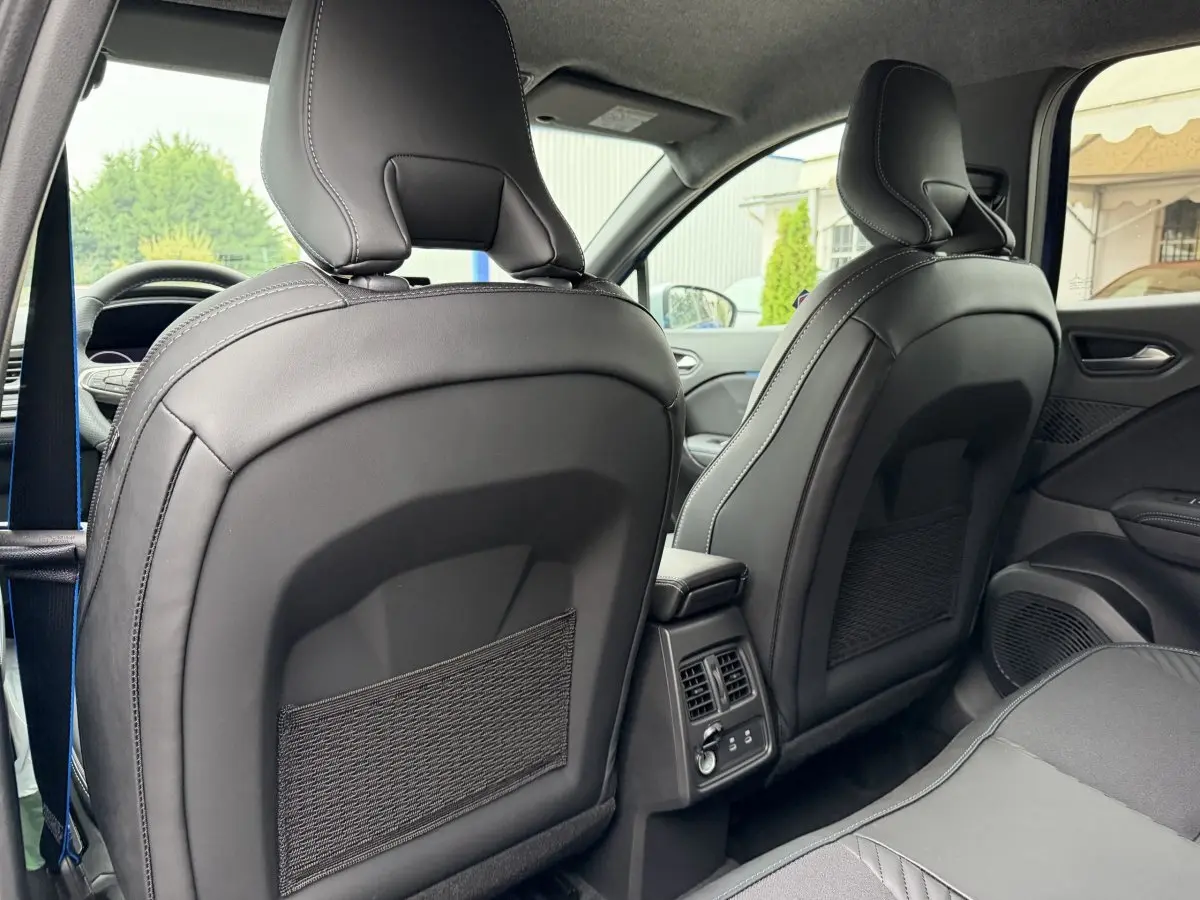 Vue arrière intérieure des sièges avant en cuir noir du Renault Captur bleu esprit Alpine full hybrid 2026, avec console centrale et aérateurs.
