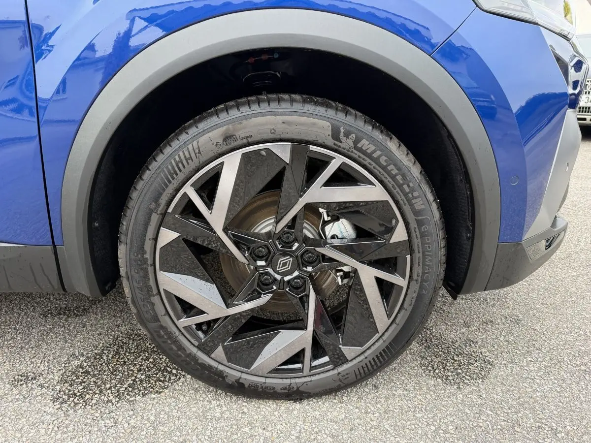Gros plan sur la roue avant droite du Renault Captur bleu esprit Alpine, jante alliage au design géométrique noir et argent.