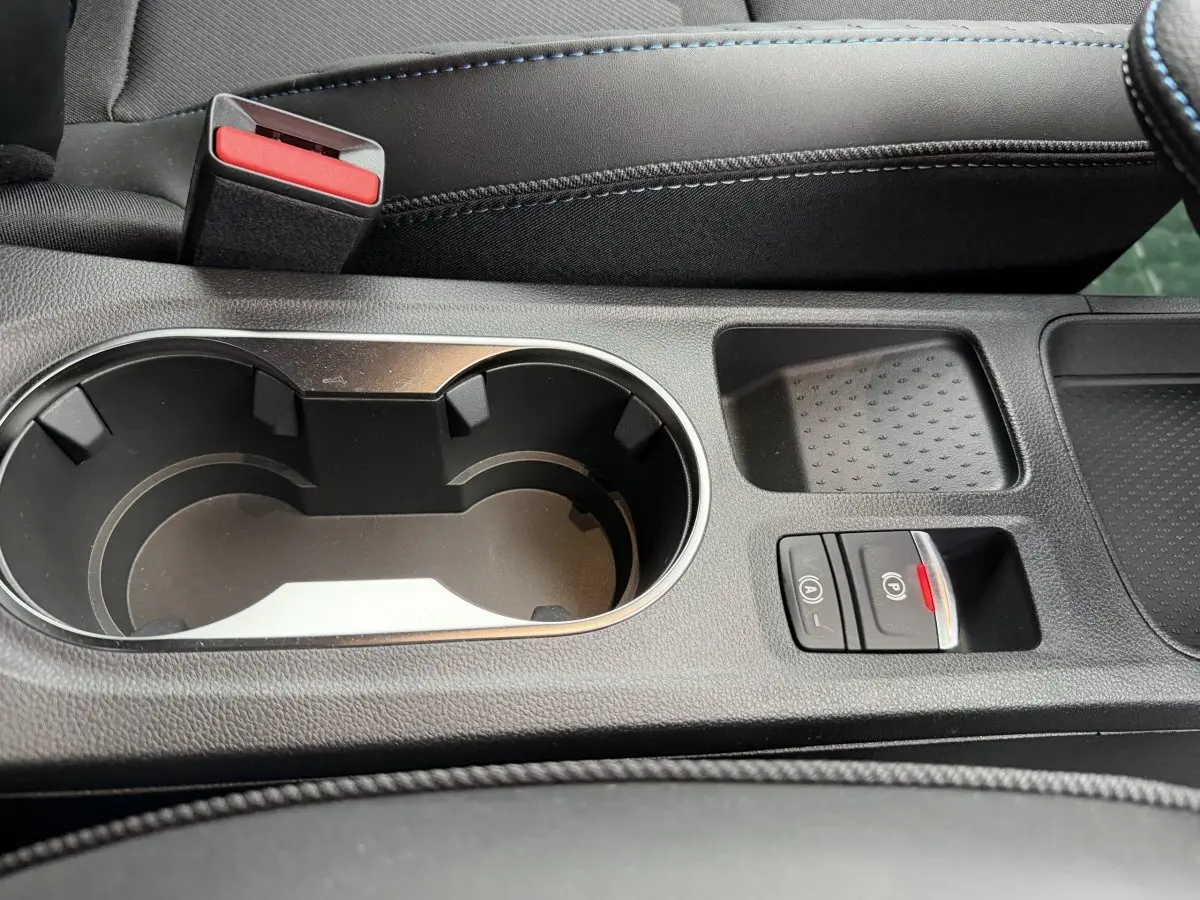 Gros plan sur la console centrale noire du Renault Captur 2026 avec porte-gobelets et commandes frein à main électrique.