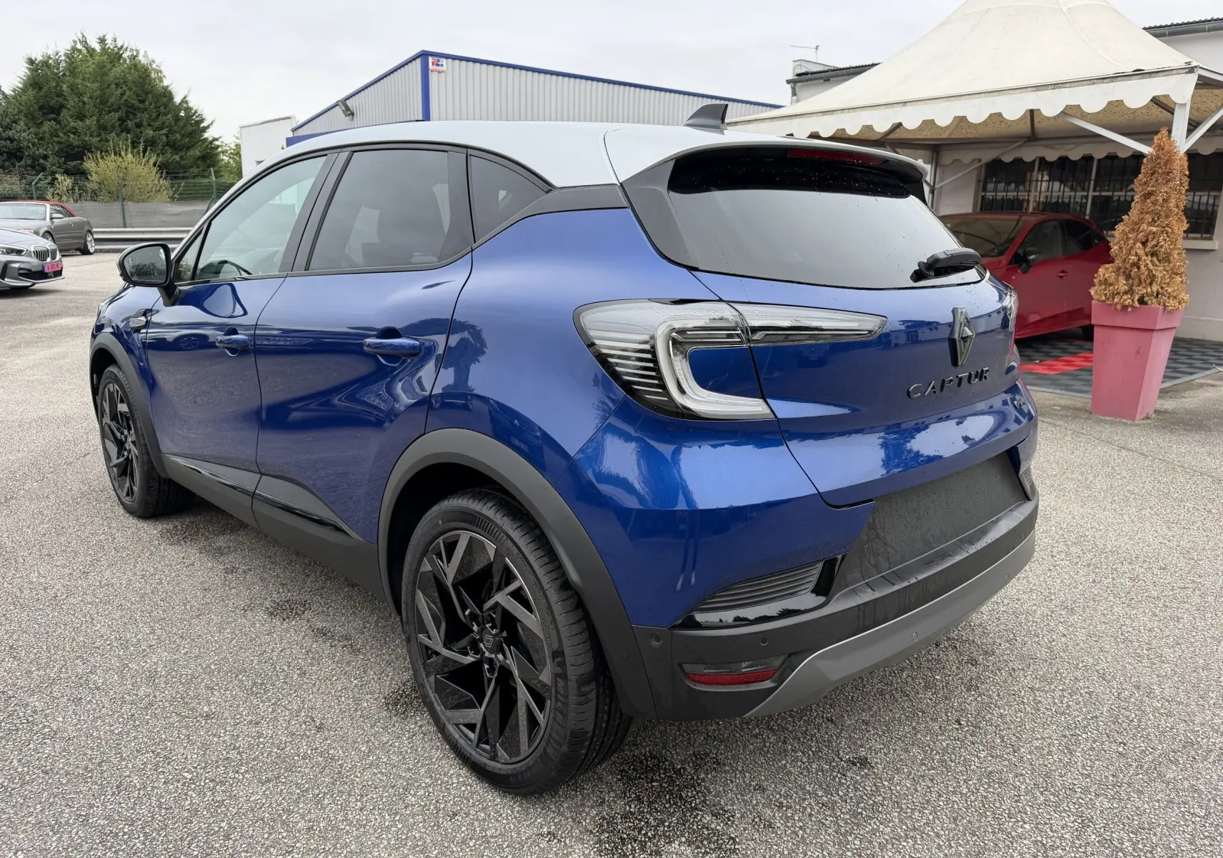 Renault Captur Esprit Alpine bleu, vue 3/4 arrière droit, toit blanc et jantes noires distinctives.