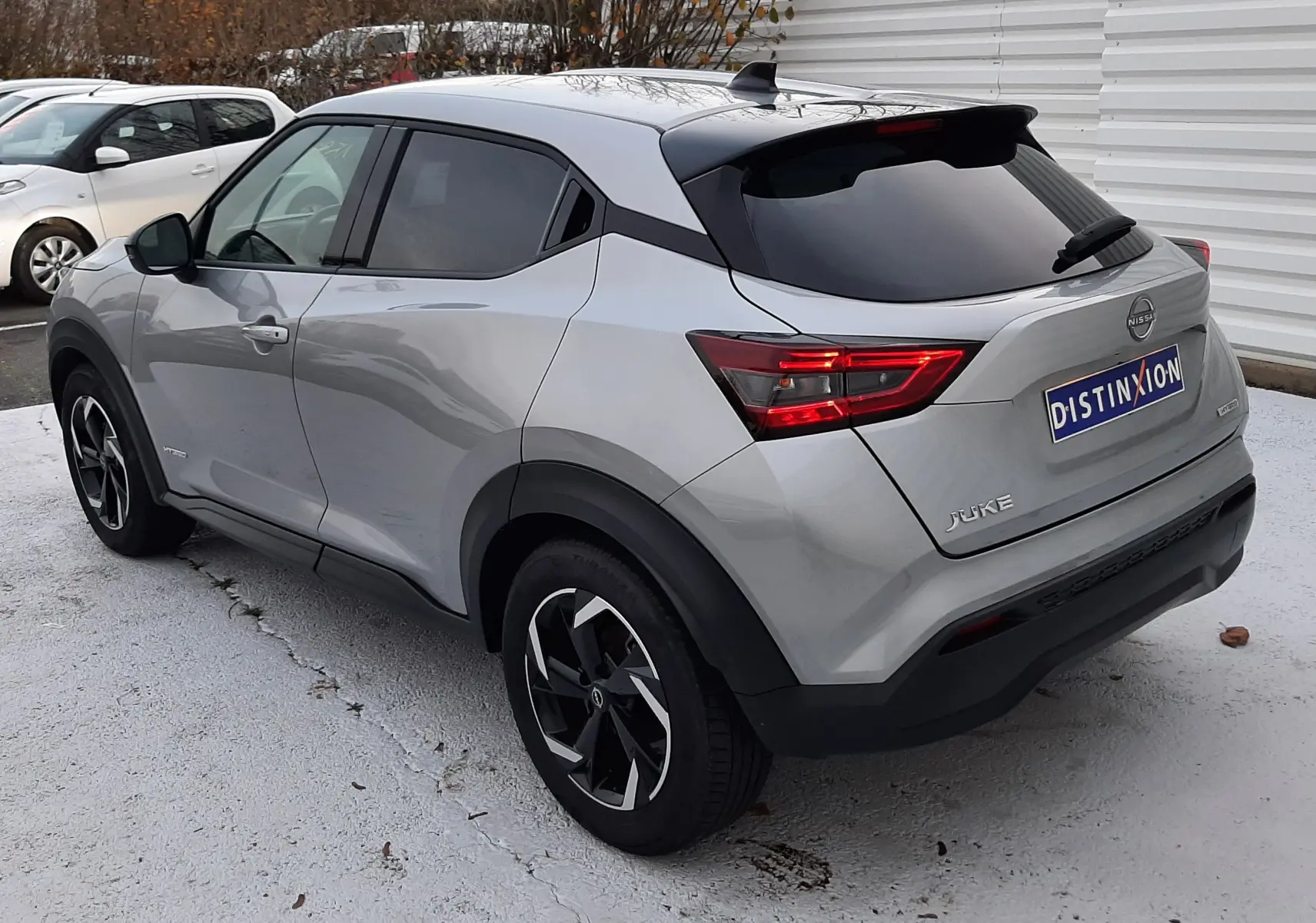 Nissan Juke 2024 gris perle métal vu en 3/4 arrière droit, avec feux arrière LED et toit noir contrasté.