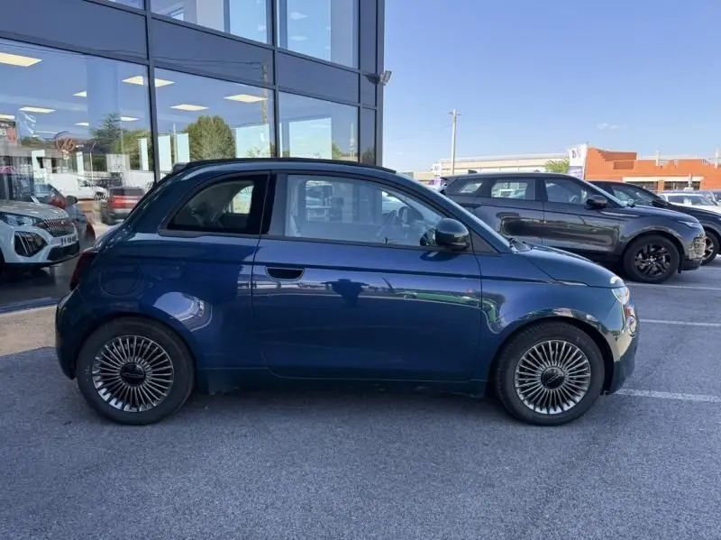 Profil côté gauche d'une FIAT 500C 118 cv icone électrique 2021 en vert foncé métallisé, roues au design distinctif.