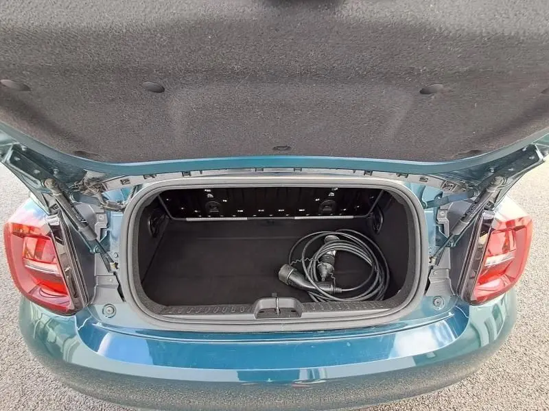 Coffre ouvert vu de l'arrière d'une FIAT 500C électrique 2021 vert foncé métallisé avec câble de recharge visible.