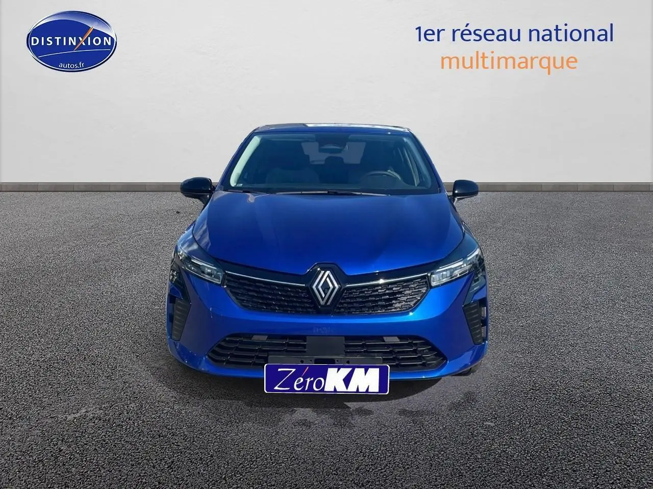 Vue avant d'une Renault Clio V bleu iron avec calandre noire et phares LED allumés sur fond neutre.