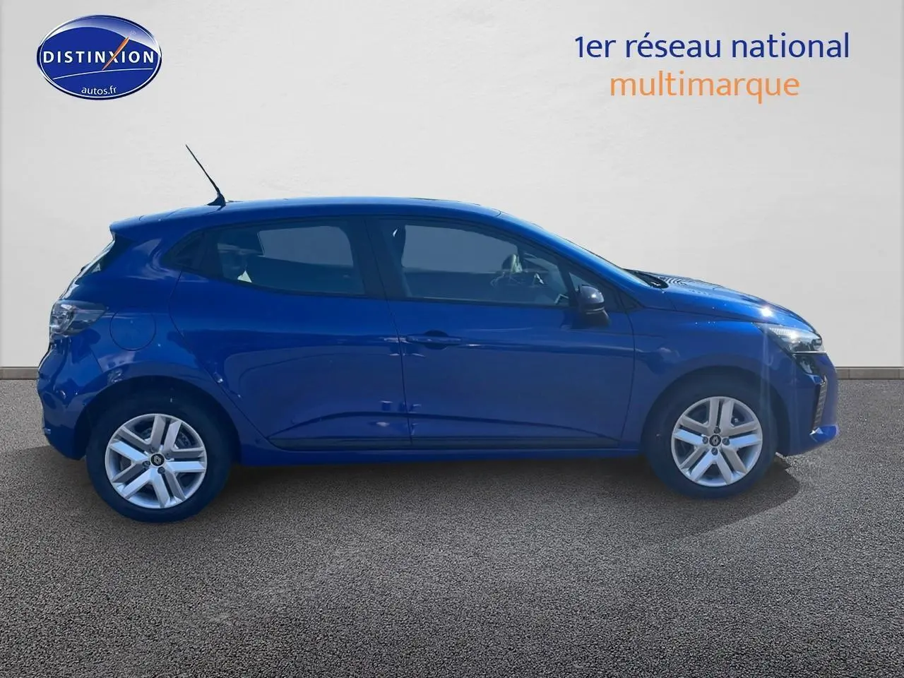 Profil côté gauche de la Renault Clio V bleu iron 2025 avec jantes alliage et vitres teintées sur fond neutre.