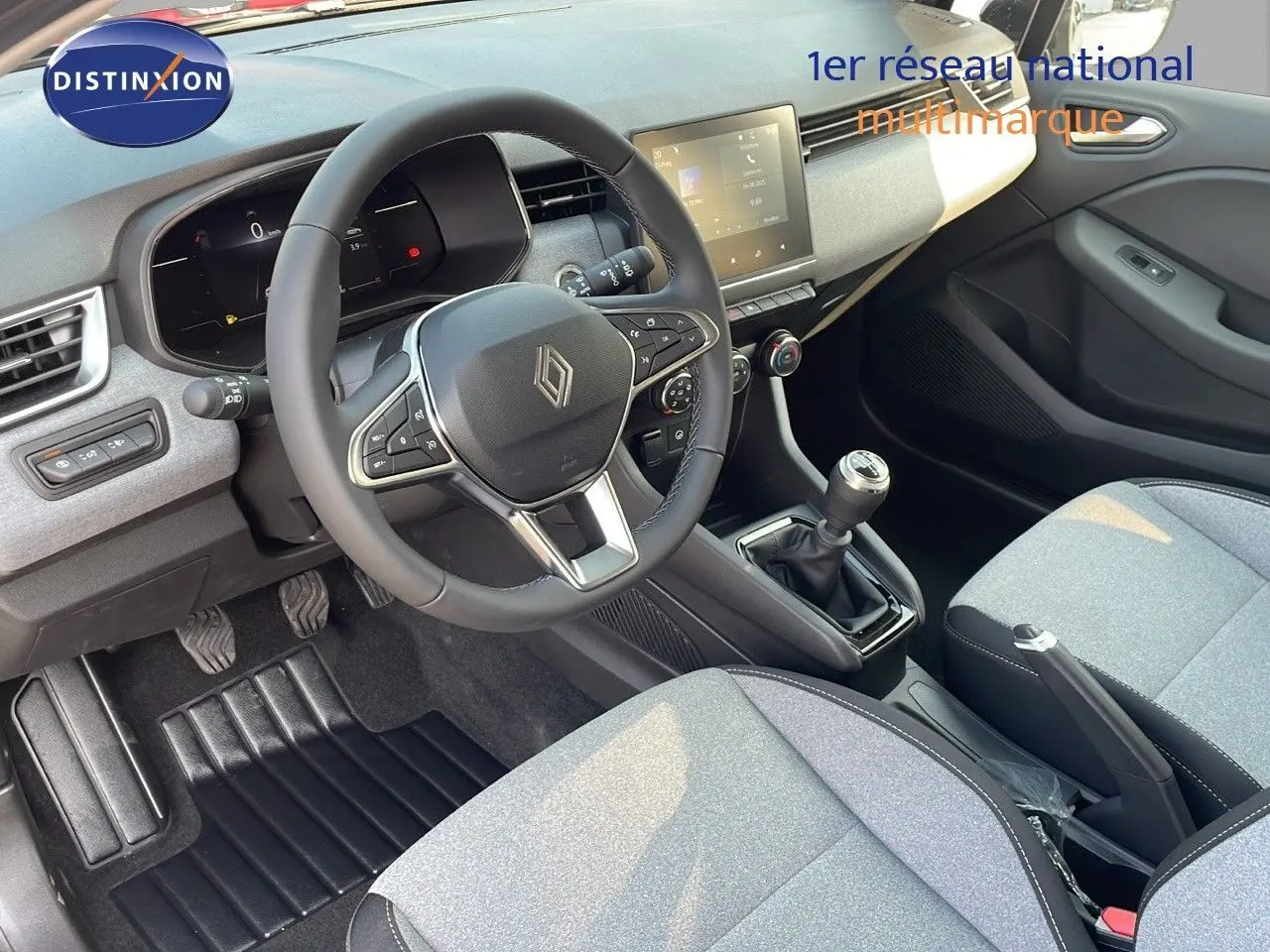 Intérieur de la Renault Clio 1.5 DCI 2025, vue du poste de conduite côté gauche avec volant, tableau de bord digital et sièges gris.