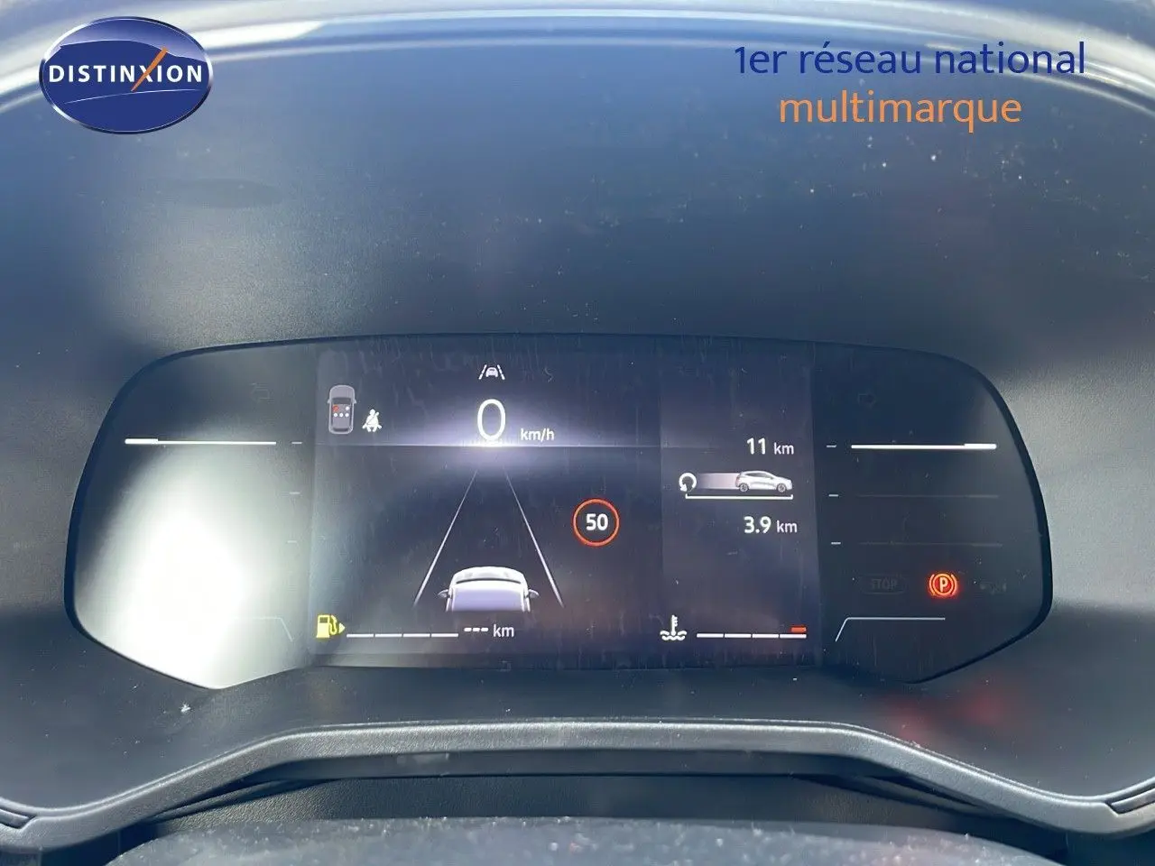 Tableau de bord numérique de la Renault Clio 1.5 DCI 100ch Evolution affichant la vitesse et alertes, vue frontale.