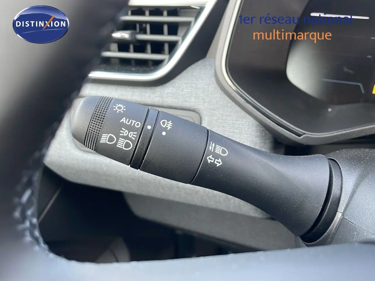 Gros plan sur la commande des phares à gauche du volant d'une Renault Clio 1.5 DCI 100CH Evolution noire étoile métal, 2025.