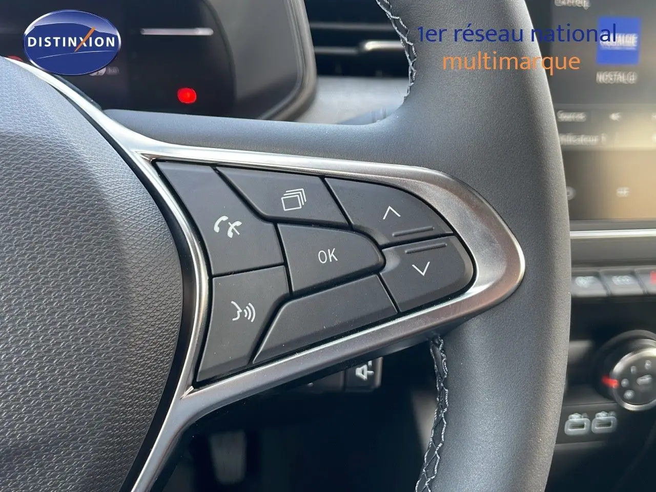 Gros plan sur les commandes multifonctions à droite du volant d'une Renault Clio noire étoile métal, intérieur moderne.