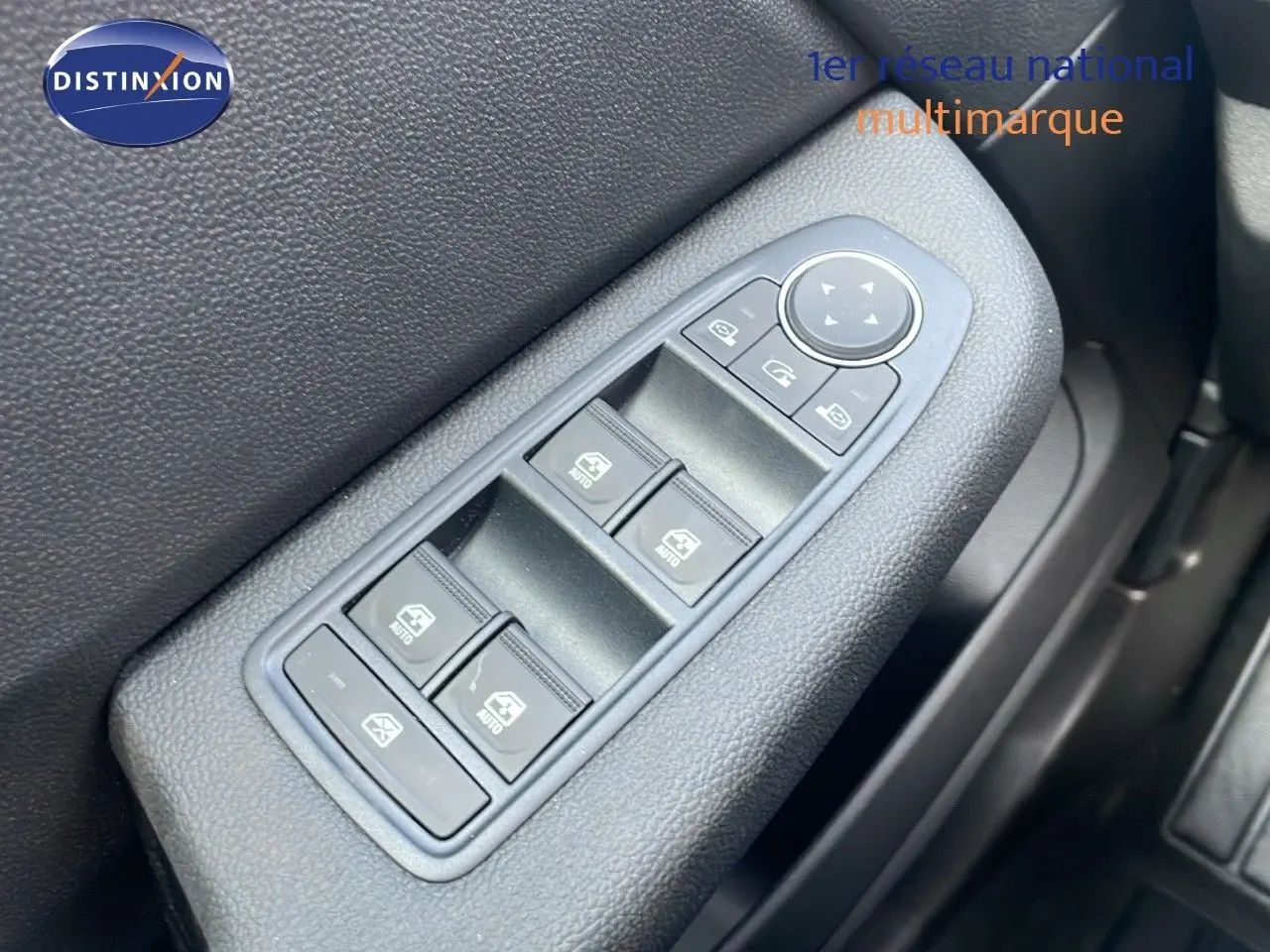 Gros plan sur les commandes des vitres électriques côté gauche de la Renault Clio noire étoile métal 2025.