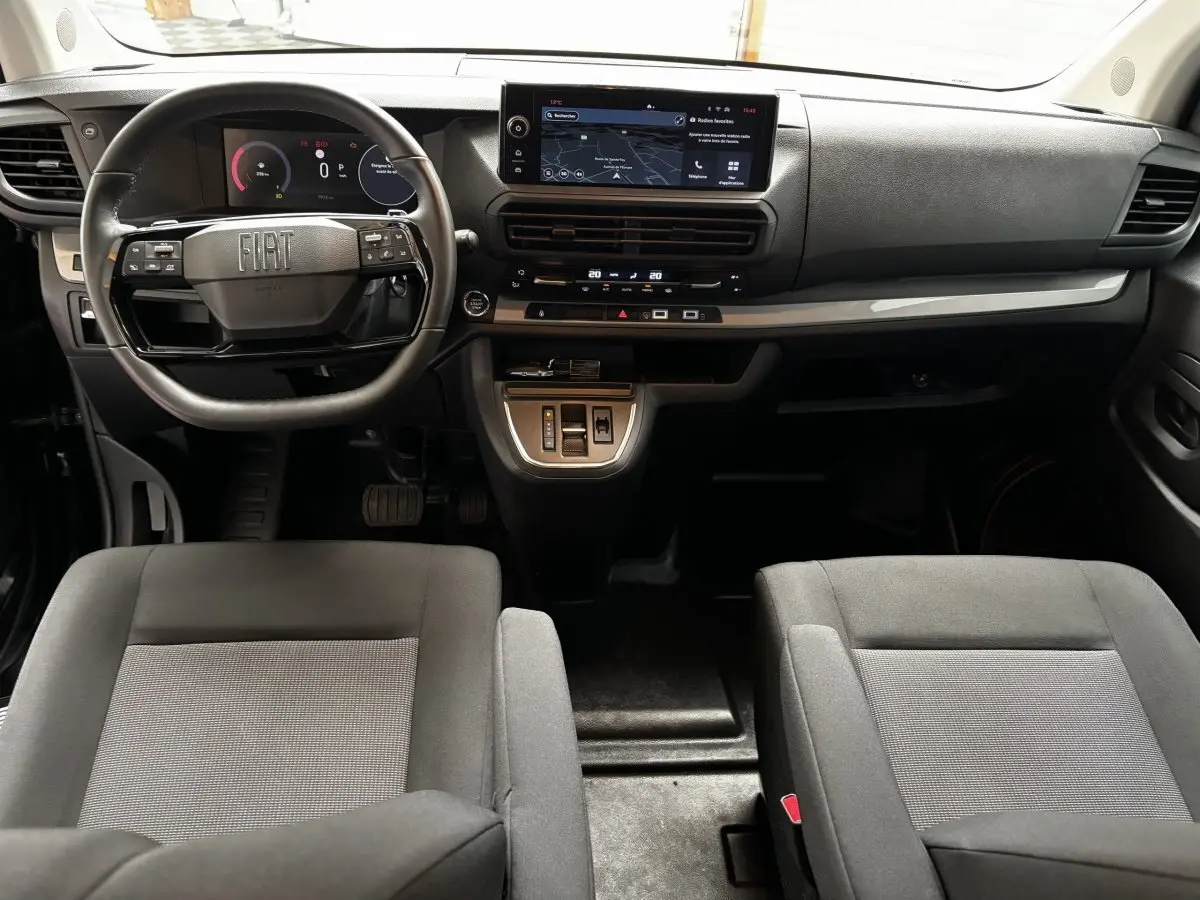 Vue intérieure avant du Fiat Scudo Fourgon 2025 noir, tableau de bord moderne avec écran tactile et volant multifonction.