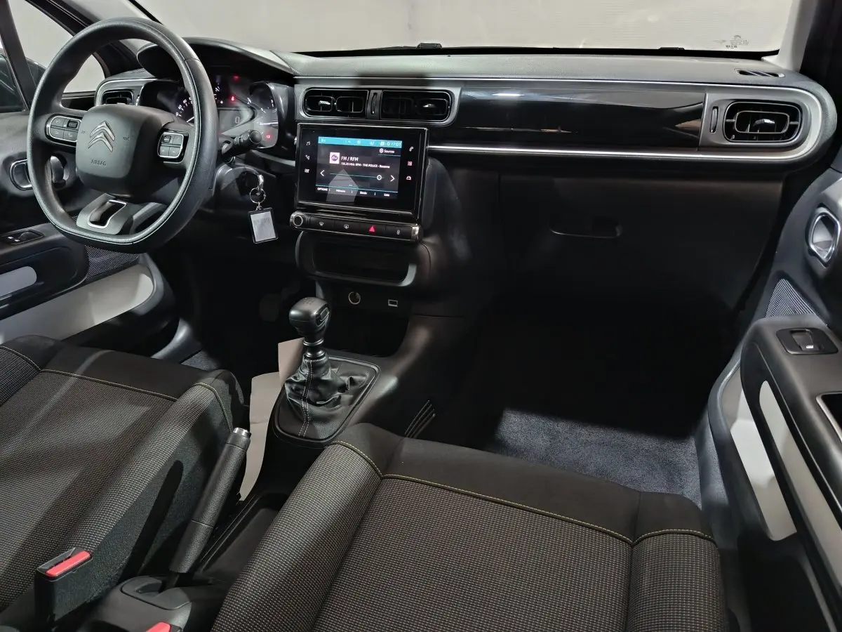 Vue intérieure côté conducteur de la Citroën C3 2024 gris foncé, avec volant multifonctions et écran tactile central.