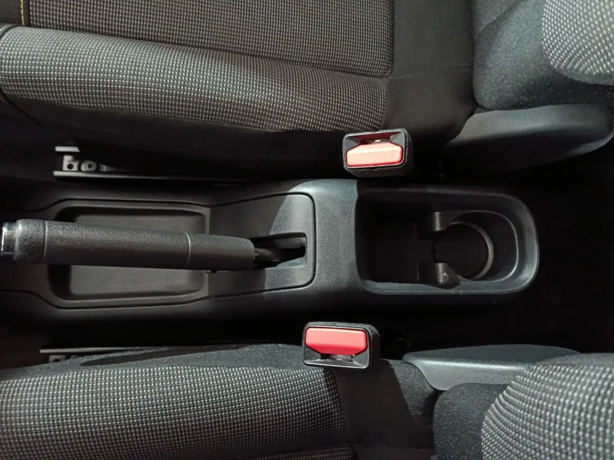 Vue plongeante sur la console centrale noire de la Citroën C3 2024 avec frein à main manuel et sièges gris foncé.