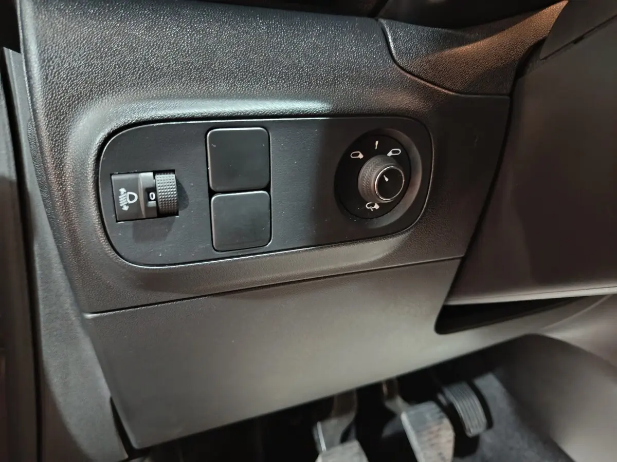 Vue rapprochée sur les commandes de réglage des rétroviseurs et des phares côté gauche d’une Citroën C3 gris foncé 2024.