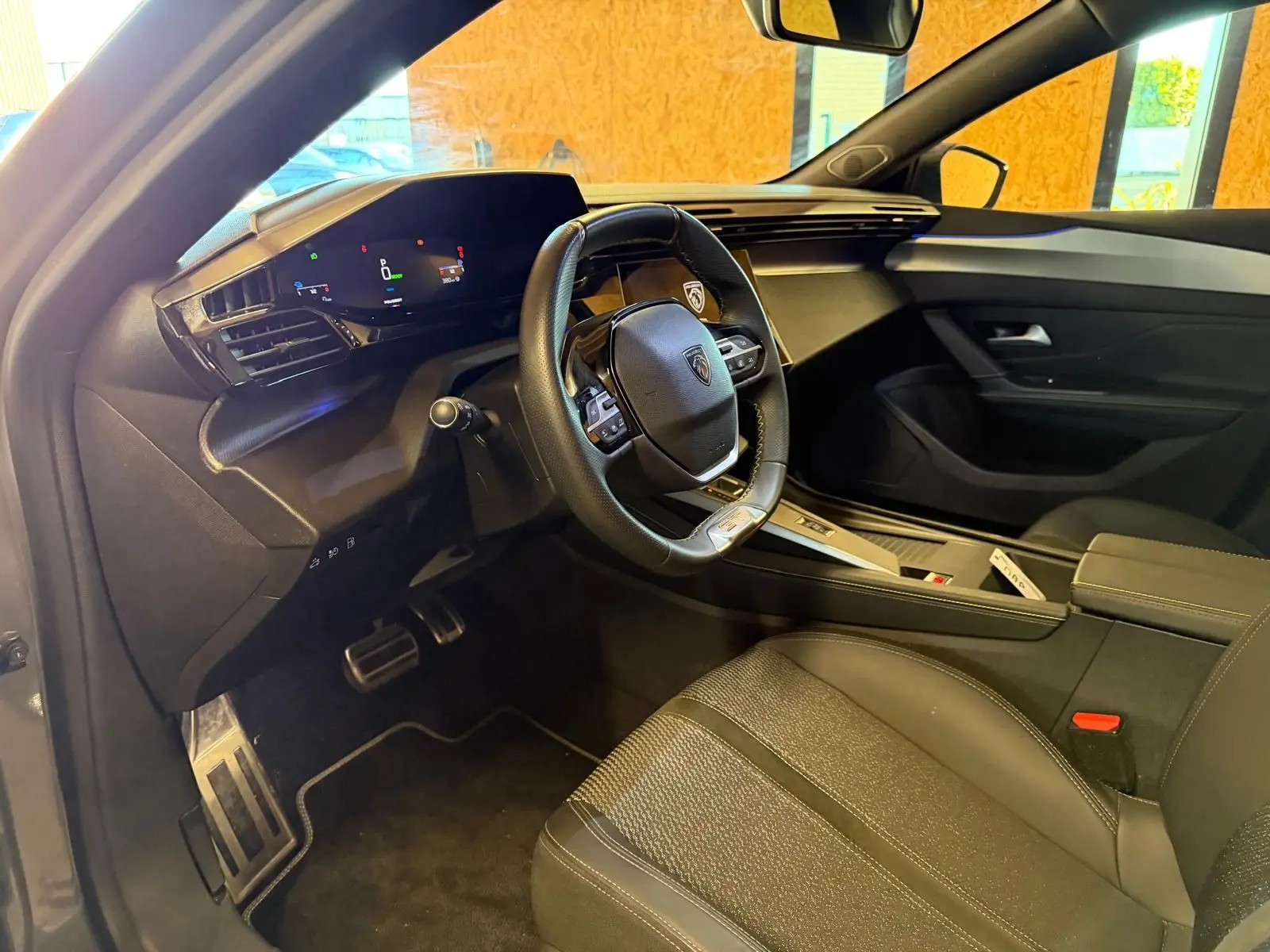 Intérieur avant droit du Peugeot 408 gris, volant compact, tableau de bord numérique et sellerie tri matières.