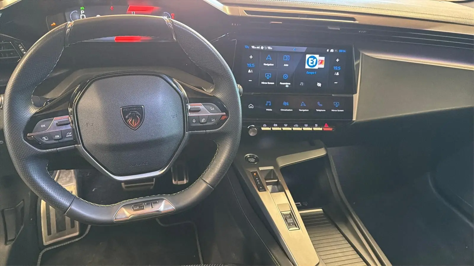 Vue intérieure centrée sur le volant GT noir et l'écran tactile 10 pouces du tableau de bord du Peugeot 408 gris.