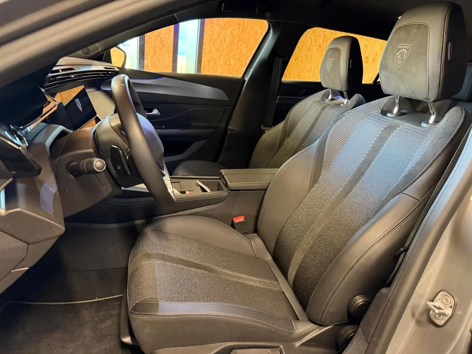 Vue intérieure côté conducteur de la Peugeot 408 gris, sièges tri matières avec logo Peugeot brodé sur appuis-tête.