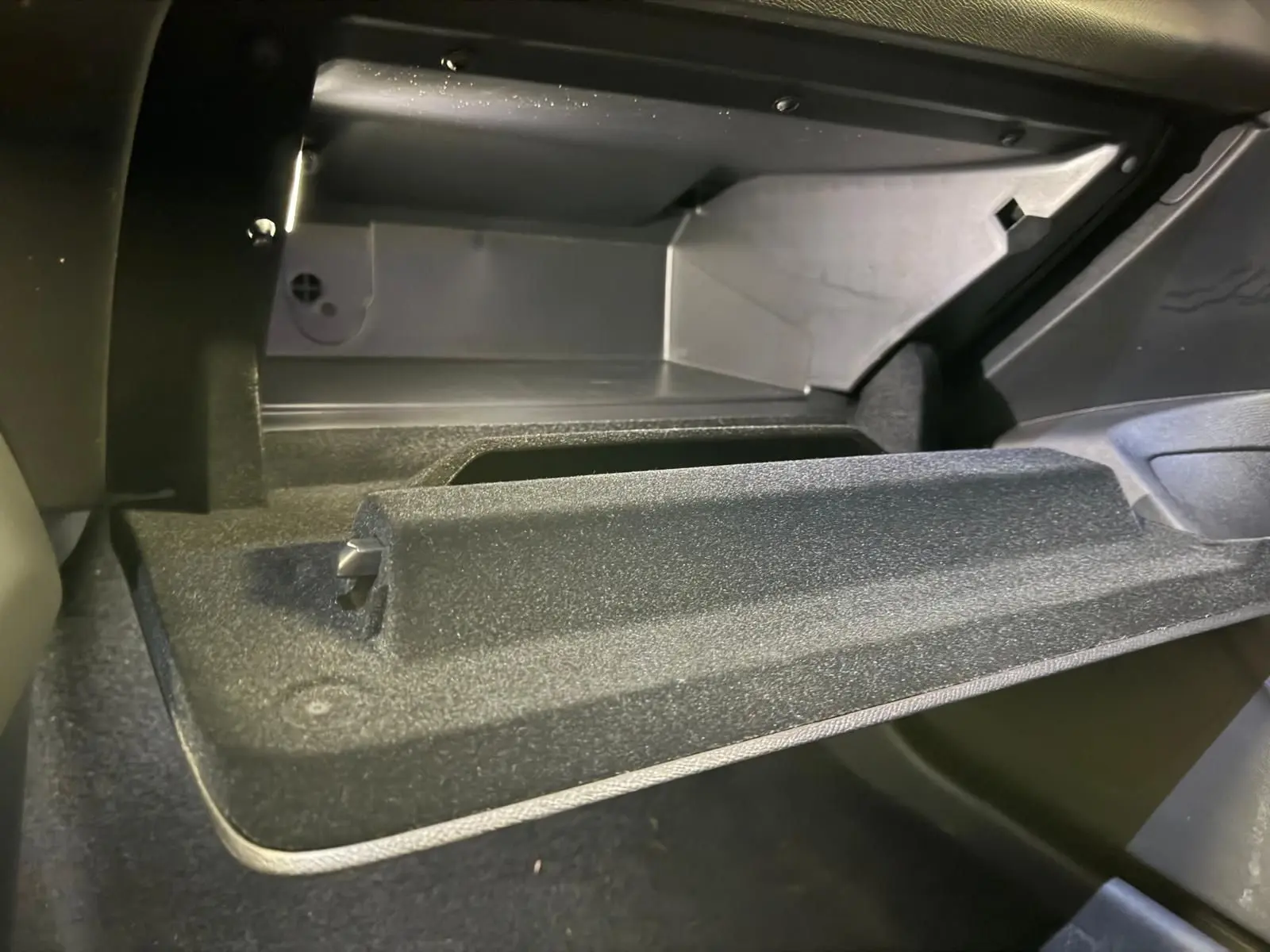 Gros plan sur la boîte à gants ouverte de la Peugeot 408 gris, montrant l'intérieur spacieux et les finitions textiles.