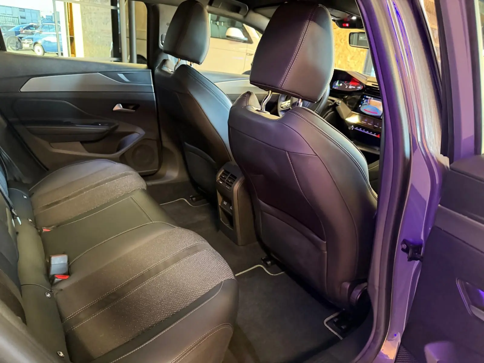 Vue intérieure arrière droite de la Peugeot 408 gris, montrant les sièges bi-matière et la console centrale avec aérateurs.