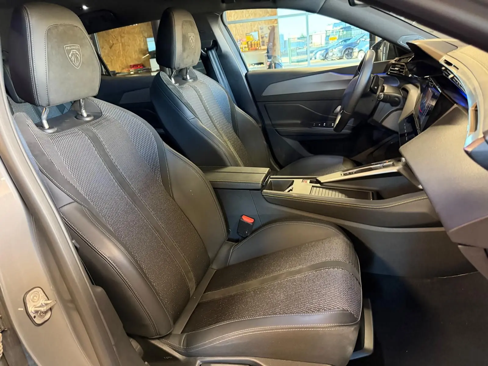 Vue intérieure côté conducteur de la Peugeot 408 gris, sièges tri matières avec logo Peugeot embossé sur appuie-tête.
