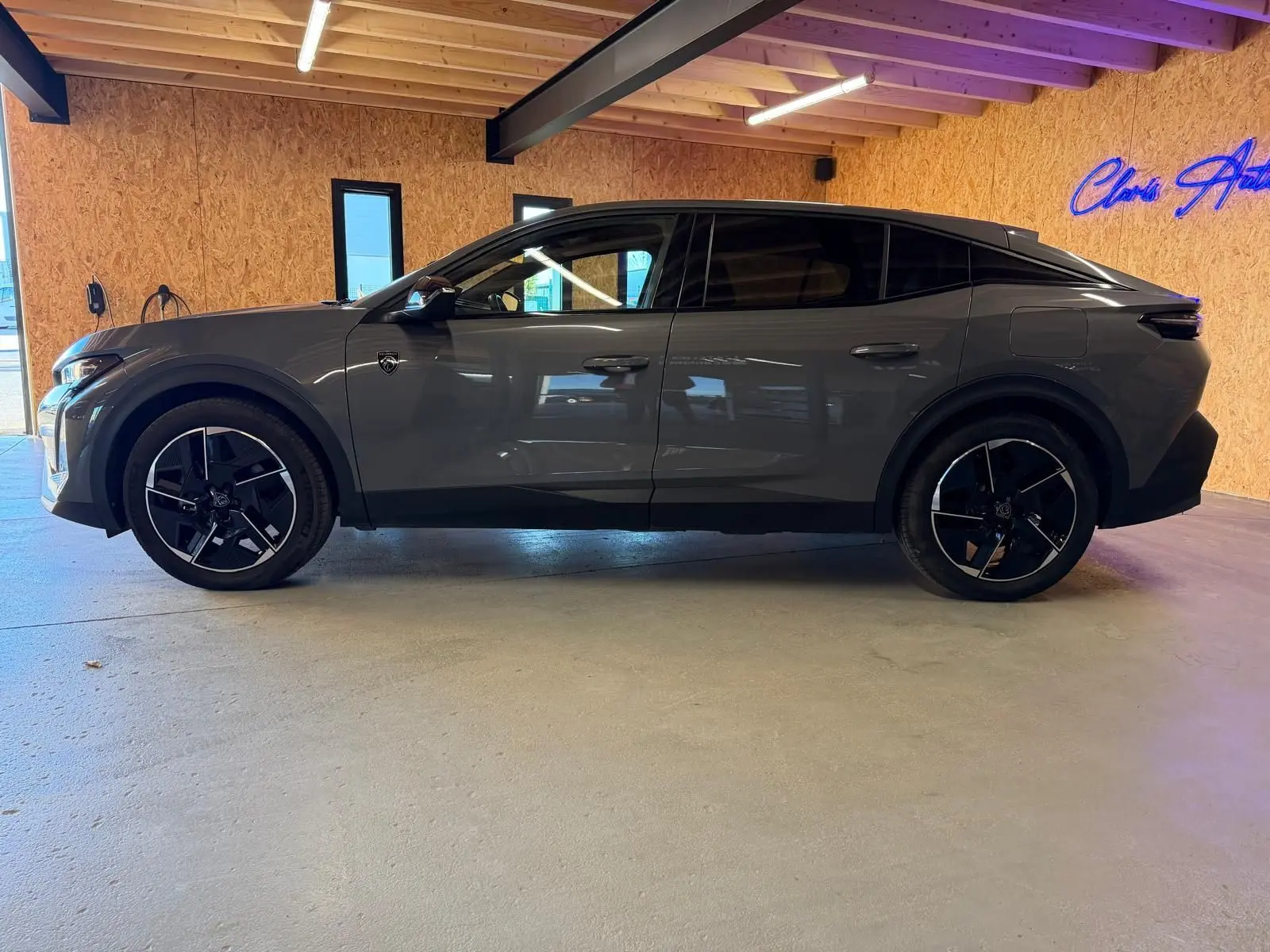Vue de profil côté gauche d'une Peugeot 408 gris métallisé avec jantes 19'' diamantées et vitres surteintées dans un garage.
