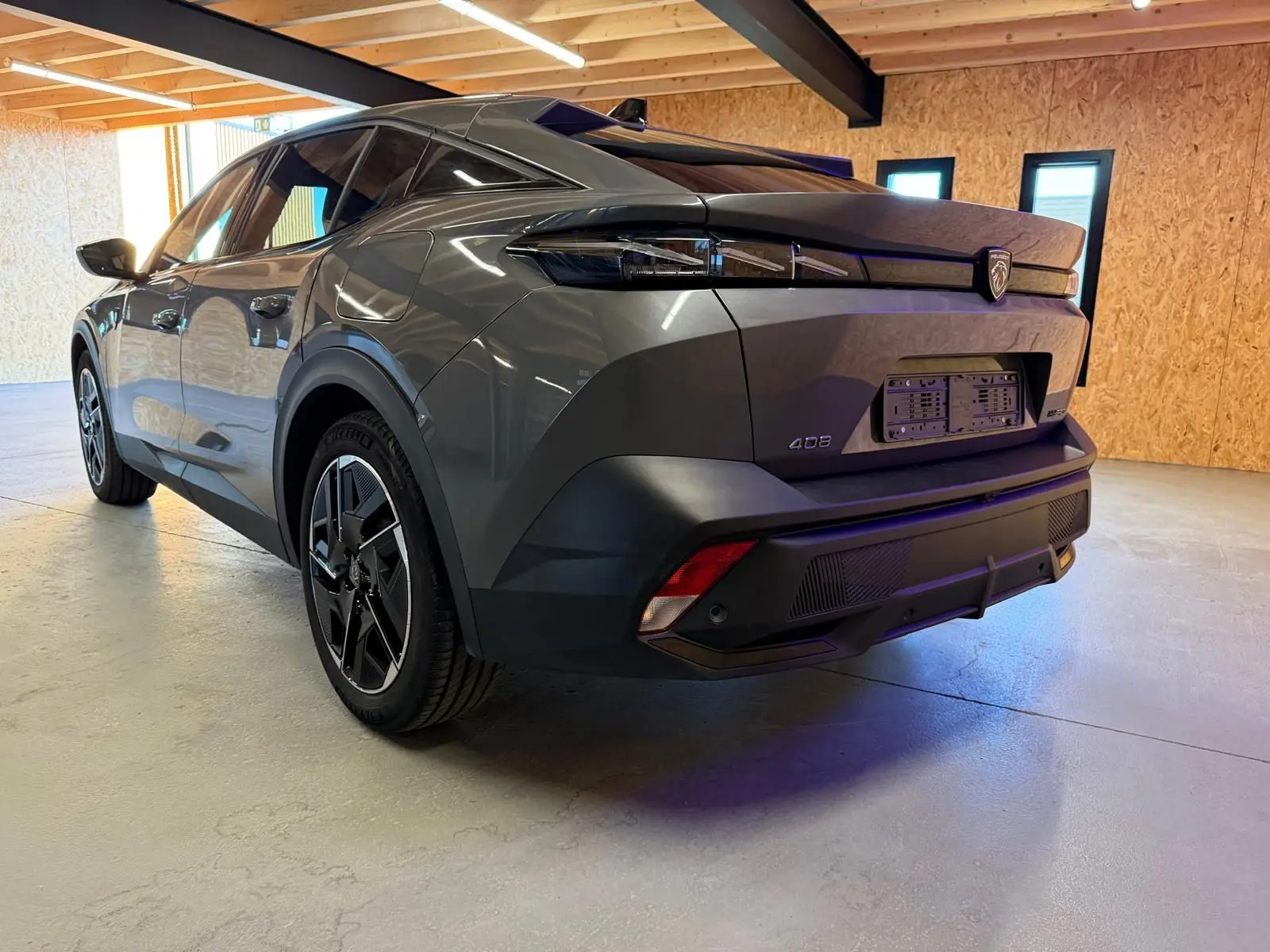 Vue 3/4 arrière droite d'une Peugeot 408 gris selenium avec jantes 19'' diamantées graphite dans un garage.