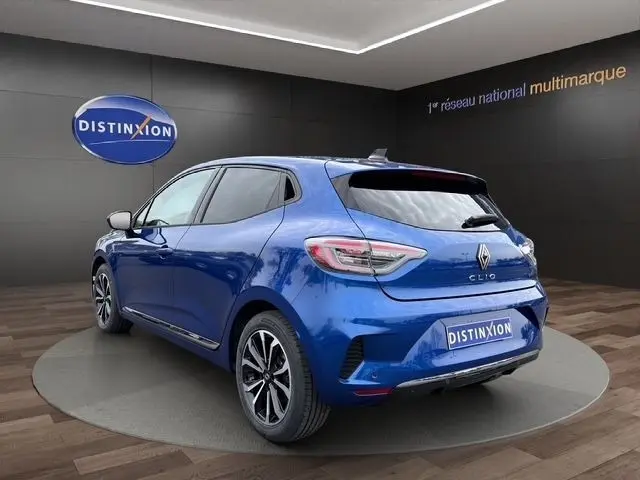Vue 3/4 arrière droite d’une Renault Clio Techno E-Tech hybride bleue, avec feux LED et jantes alliage distinctives.