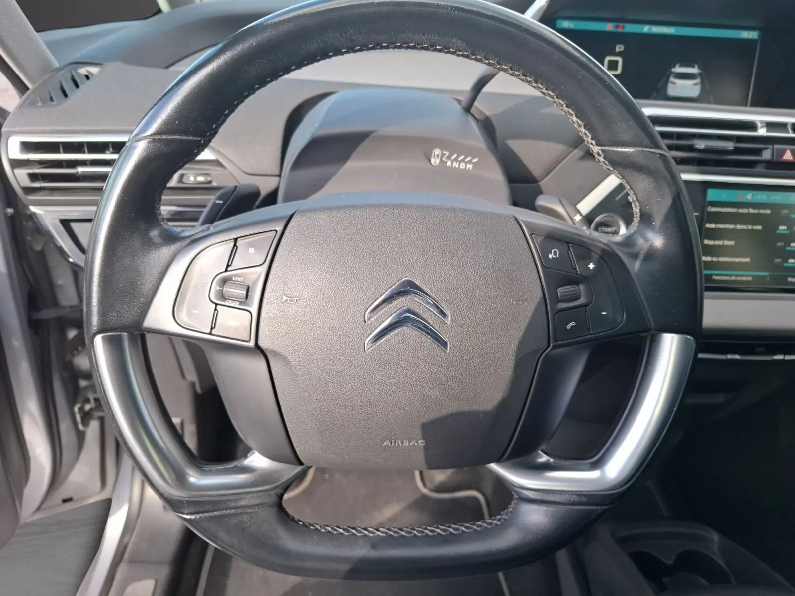 Vue rapprochée du volant cuir noir de la Citroën C4 Picasso 2018 avec commandes intégrées et tableau de bord visible.