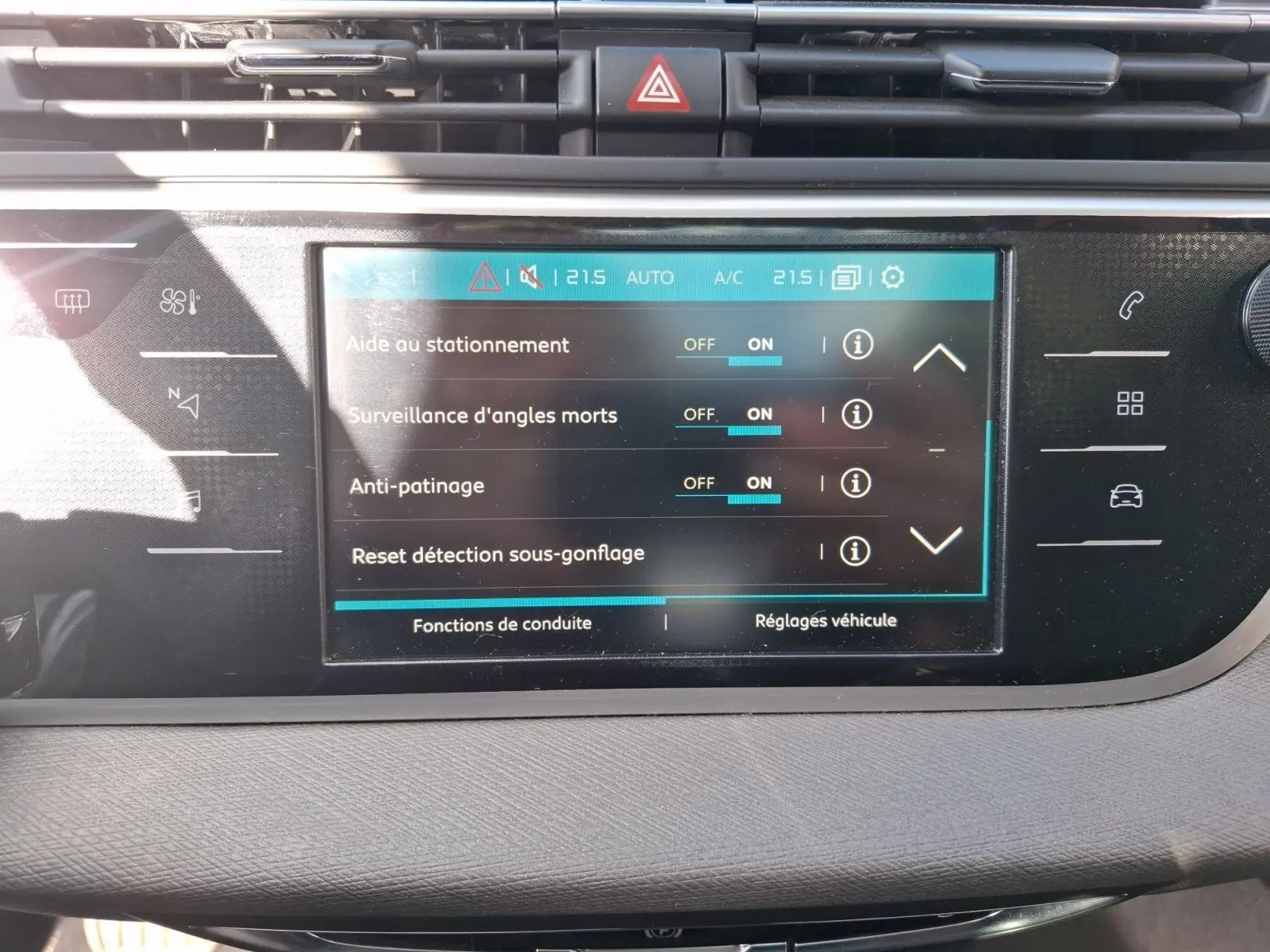 Vue rapprochée de l’écran tactile central du tableau de bord du Citroën C4 Picasso gris clair, affichant les réglages d’aide à la conduite.