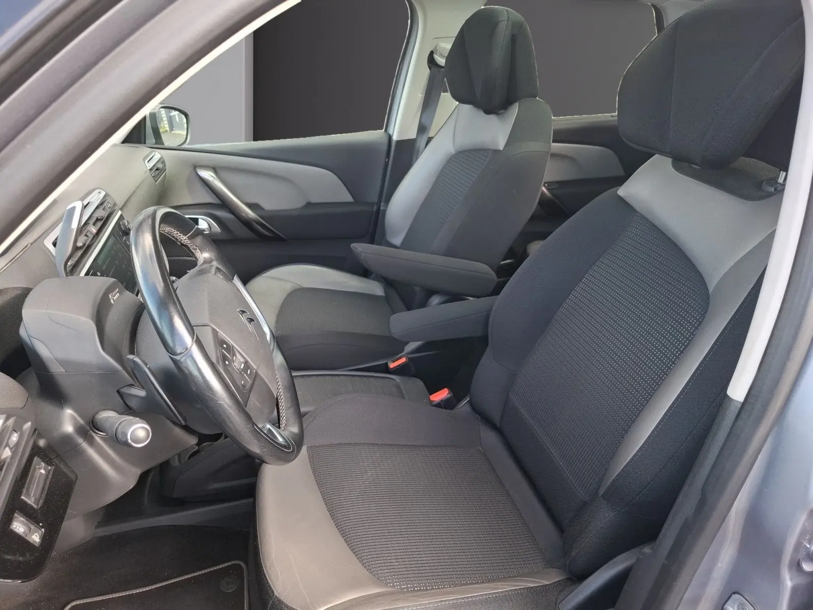 Vue intérieure côté conducteur de la Citroën C4 Picasso 2018, sièges cuir et tissu gris, volant multifonctions visible.