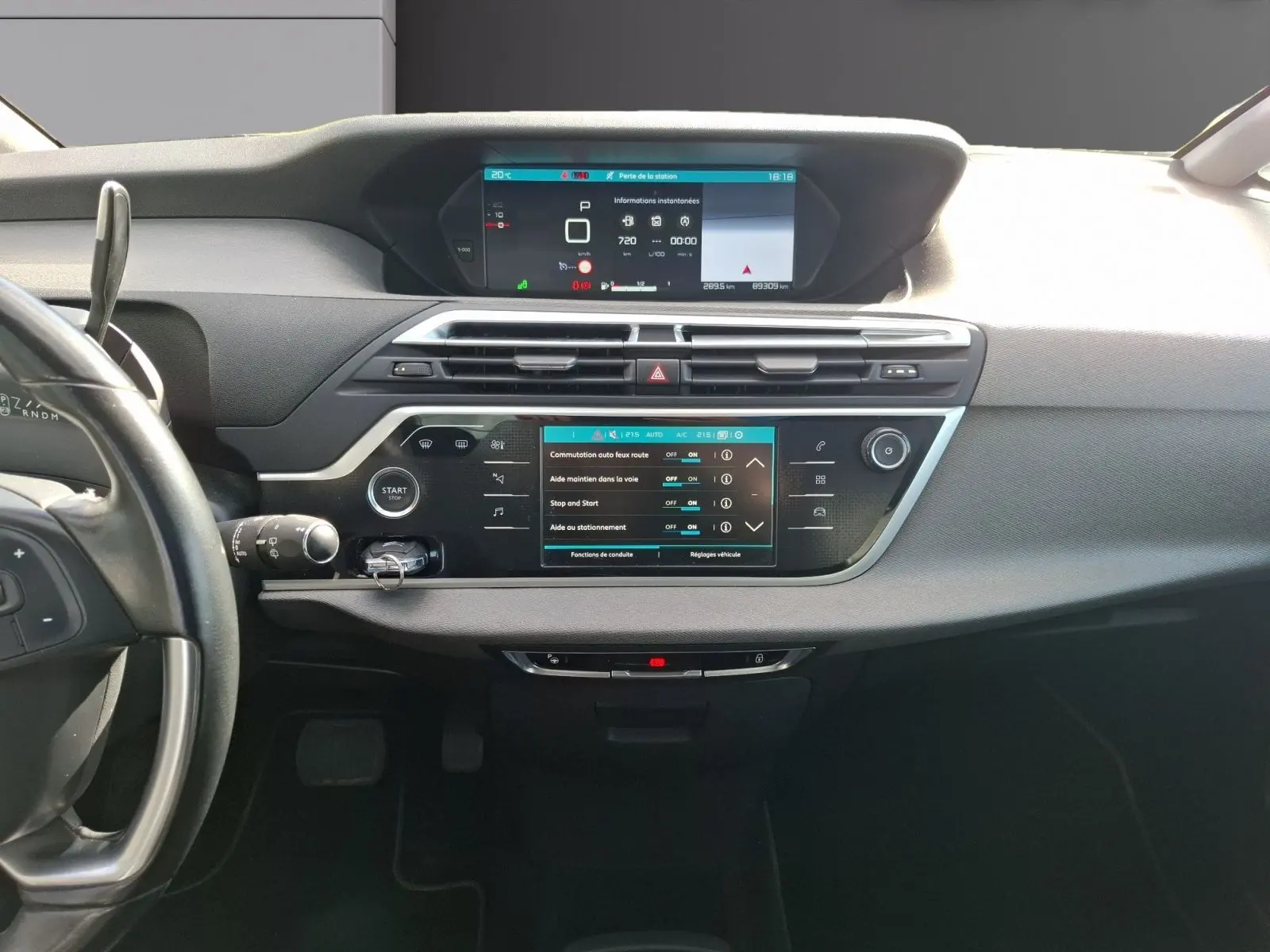Vue frontale de l’intérieur du Citroën C4 Picasso gris clair, avec tableau de bord numérique et écran tactile central.