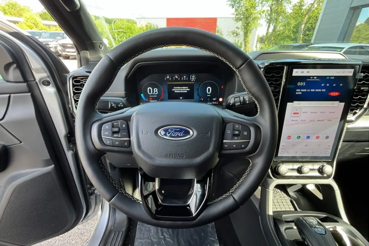 Vue intérieure centrée sur le volant cuir noir et l'écran tactile vertical du Ford Ranger gris iconic 2026.