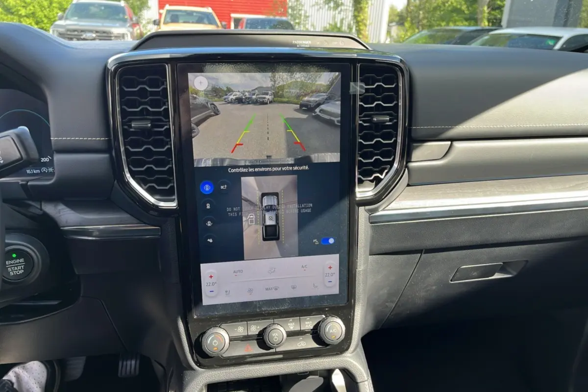 Vue intérieure centrée sur l'écran tactile vertical du tableau de bord du Ford Ranger 2026 avec commandes climatisation et caméra de recul affichée.