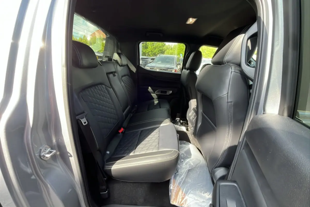 Vue intérieure arrière côté gauche du Ford Ranger gris iconic, montrant les sièges en cuir noir matelassé et le rideau coulissant.