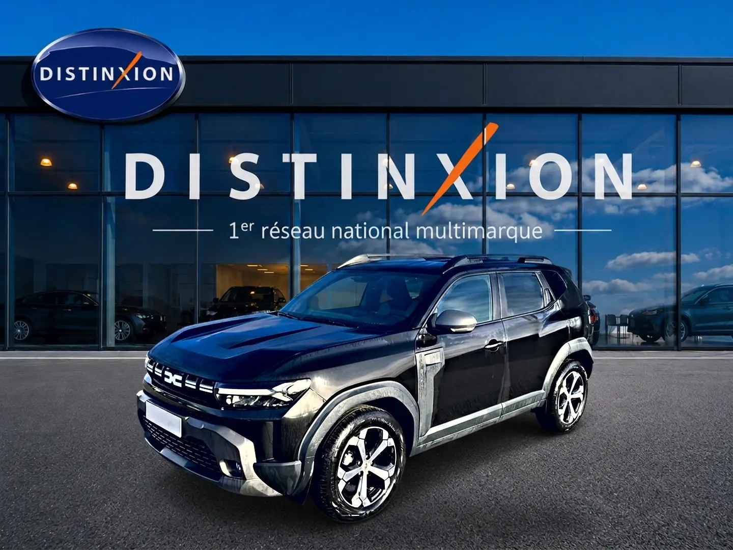 Dacia Duster noir vue 3/4 avant droit, avec jantes alu et barres de toit devant showroom Distinxion.