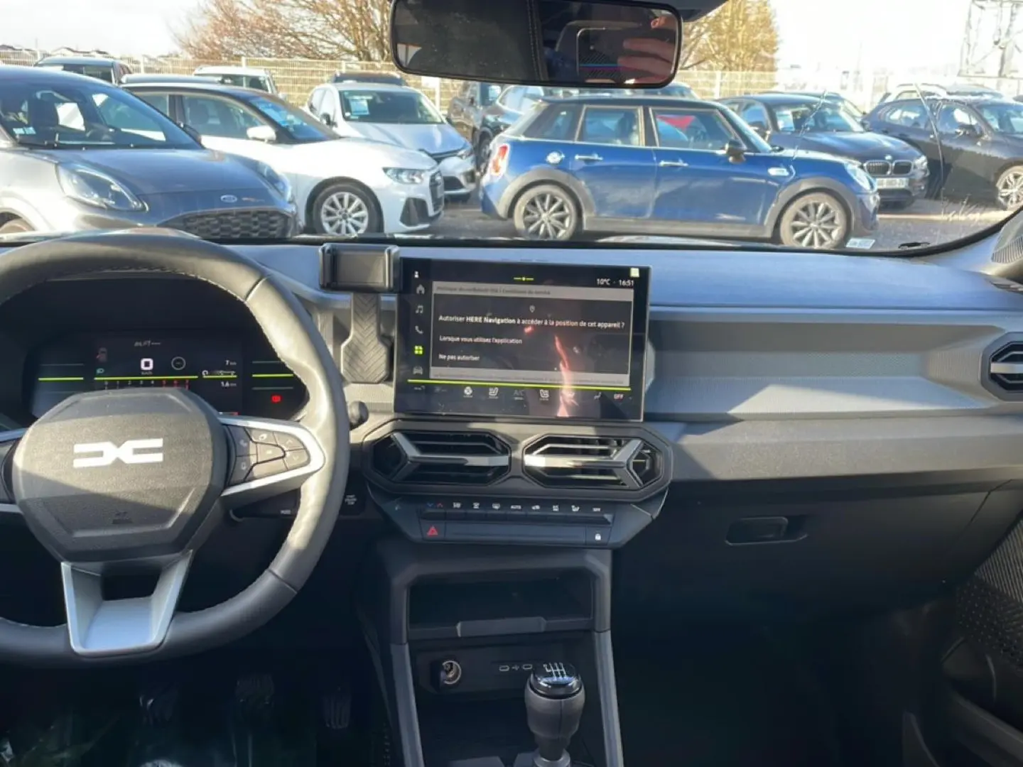 Vue intérieure avant du tableau de bord noir du Dacia Duster 2026 avec écran tactile et volant multifonction.