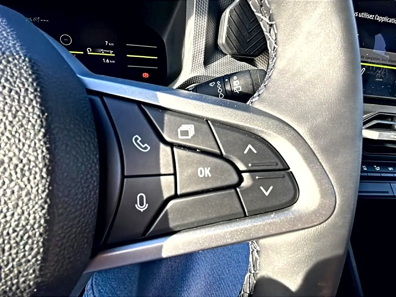 Gros plan sur les commandes multifonctions du volant noir du Dacia Duster 2026, avec écran tactile en arrière-plan.