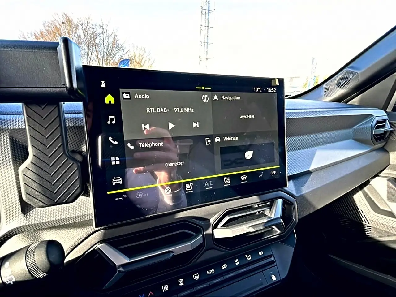 Vue intérieure du tableau de bord du Dacia Duster 2026 noir, avec écran tactile multifonction et aérateurs angulaires.