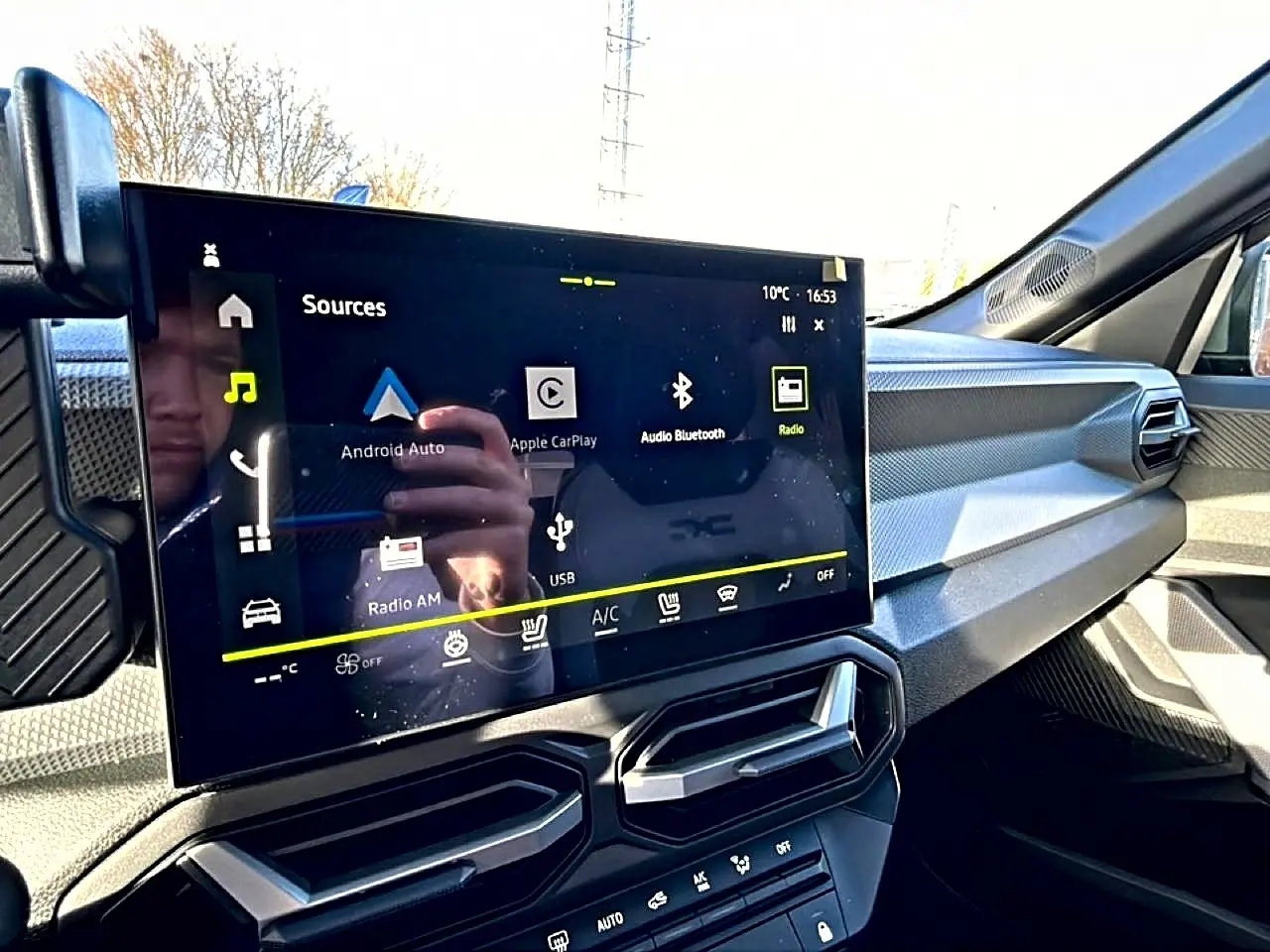 Vue intérieure du tableau de bord du Dacia Duster 2026, écran tactile multifonction et aérateurs hexagonaux noirs.