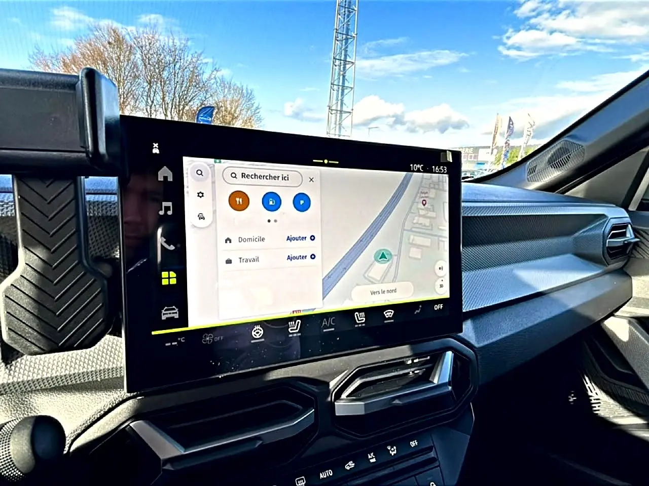 Vue intérieure du tableau de bord du Dacia Duster 2026 avec écran tactile GPS et commandes climatisation visibles.