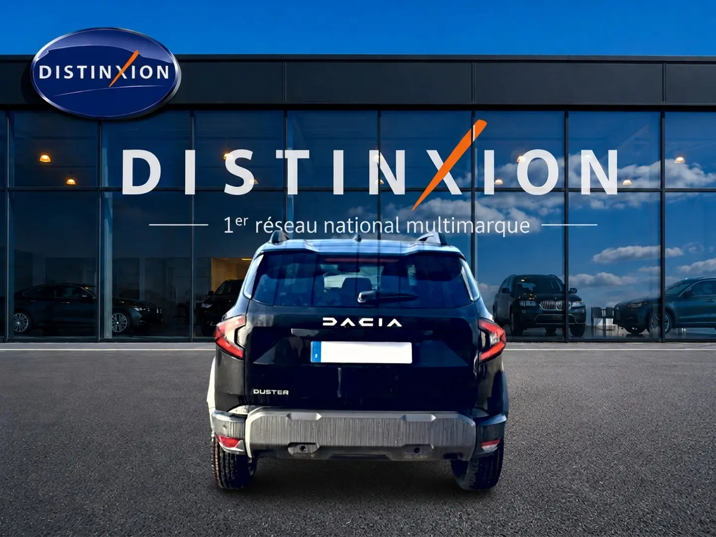 Vue arrière d'un Dacia Duster noir 2026, avec barres de toit et logo distinctif sur fond de vitrine Distinxion.