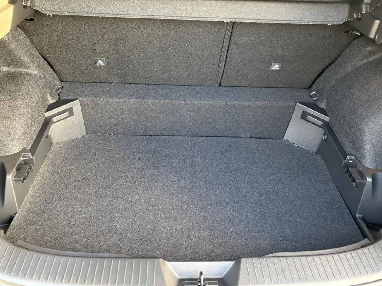Coffre spacieux et propre du Nissan Qashqai III e-Power 2026, vue intérieure arrière avec revêtement gris foncé.